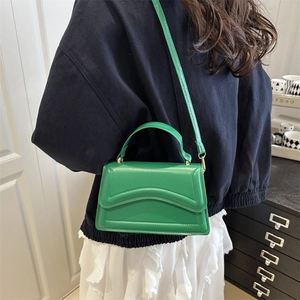 Minimalist green leather square handbag with wave pattern shown on model outfit