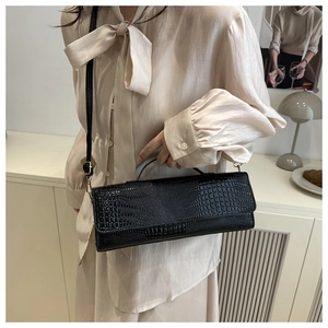 Detail view of black crocodile pattern faux leather handbag with elegant gold hardware