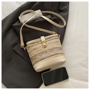 Dettaglio di una borsa a secchiello intrecciata beige con base in pelle e chiusura d'oro