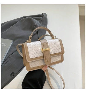 Detailed shot of white woven crossbody bag with gold buckle and faux leather trim
