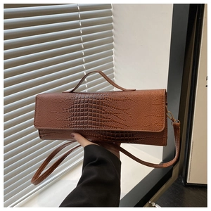 Close-up of brown crocodile texture on rectangular shoulder bag with top handle