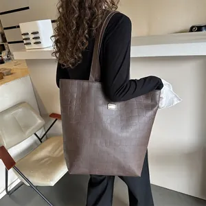 Sac cabas marron à motif crocodile avec plaque argentée porté à l'épaule