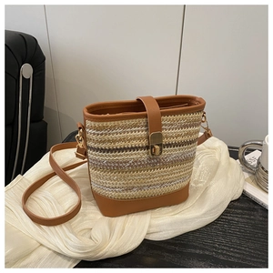 Dettaglio borsa a secchiello intrecciata con finiture in pelle marrone e fibbia dorata