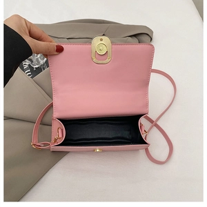 Detail view of pink crossbody bag open with metal twist lock and black fabric lining