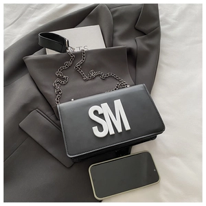 Détail du sac bandoulière en cuir noir avec lettrage SM blanc et chaîne en métal