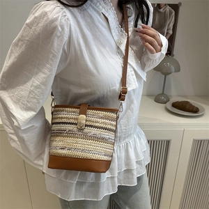 Ethnic straw bucket bag with contrast weave and leather flap in a lifestyle setting