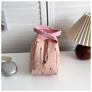 Détail d'un sac à main matelassé rose avec nœuds brodés et fermeture éclair en métal