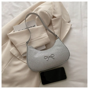 Close-up of silver sequin hobo bag featuring a metallic bow detail on beige blazer