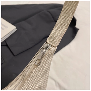 Detail shot of beige woven shoulder bag showing silver metal zipper and texture