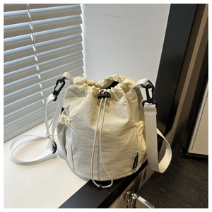 Detail der cremefarbenen Nylon-Beuteltasche mit schwarzer Netztasche und Gurtband