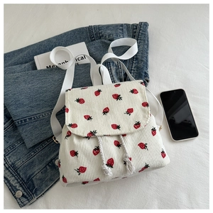 Flat lay of off-white corduroy backpack with cute strawberry pattern and drawstring closure