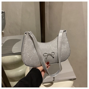 Detailed close-up of sparkling silver glitter texture and metal bow charm on crescent bag