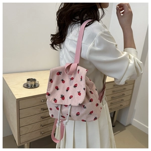 Pink corduroy backpack with strawberry print shown on model in a minimalist setting