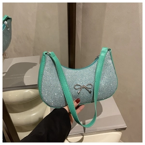Detail of mint green crystal handbag featuring a silver metal bow and rhinestone finish