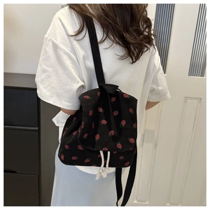 Detail of black corduroy mini backpack with red strawberry embroidery and rope drawstring