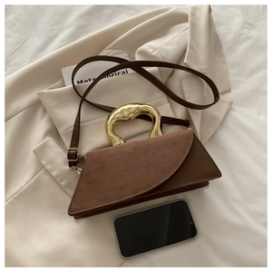Detail of brown leather handbag featuring unique gold lava-textured metal handle