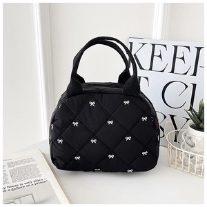 Détail de la trousse de maquillage matelassée noire avec broderies de nœuds blancs