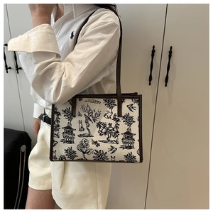 Detail of canvas tote bag featuring classic landscape prints and brown leather trim