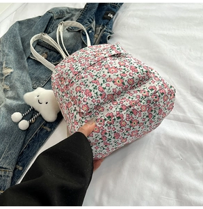 Detailansicht eines Mini-Rucksacks aus Nylon mit Blumenmuster und weißen Lederriemen