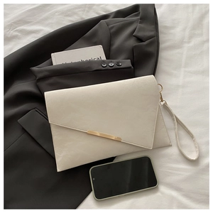 Detail of cream envelope clutch with gold metal bar and elegant leather texture
