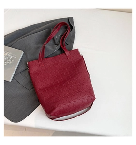 Détail d'un cabas bordeaux foncé avec motifs crânes embossés sur cuir à grain fin chic