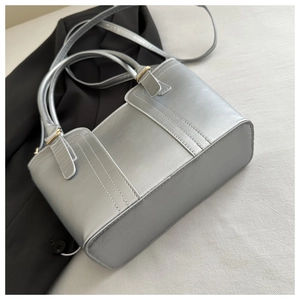 Detail of silver metallic textured handbag with gold hardware and top stitching