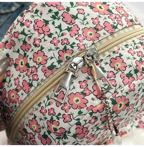 Detail eines geblümten Nylon-Rucksacks mit Doppelreißverschluss und Plüschanhänger