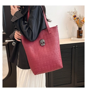 Détail d'un sac cabas bordeaux avec motifs têtes de mort et ornement en métal argenté