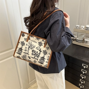 Large beige canvas tote bag with black traditional ink art and brown leather handles