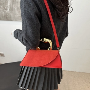 Red suede handbag with artistic gold metal handle and shoulder strap shown by a model