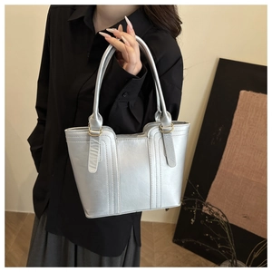 Detail of silver metallic tote bag featuring vertical stitching and golden D-ring hardware