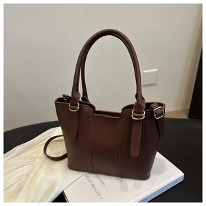 Detailed close-up of a brown tote bag featuring gold hardware and removable strap