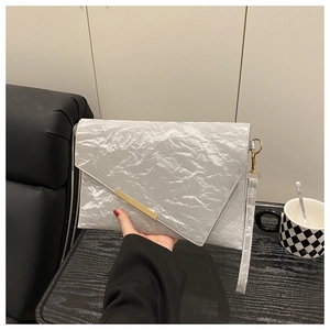 Close-up of a silver crinkled envelope clutch with a gold metal accent and wrist strap