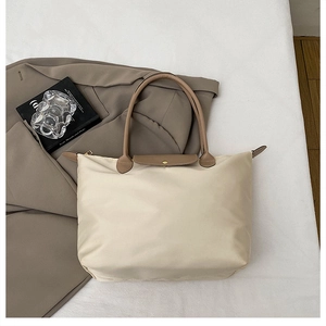 Gros plan du sac cabas en nylon beige avec poignées en cuir marron et bouton pression