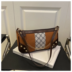 Detail of vintage patchwork shoulder bag with geometric patterns and gold chain accents