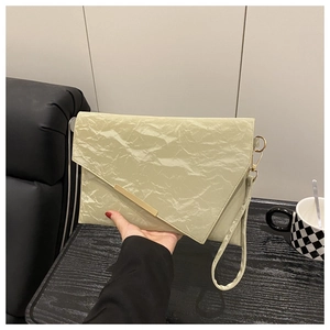Detail of light green envelope clutch bag featuring unique wrinkled texture and gold accents
