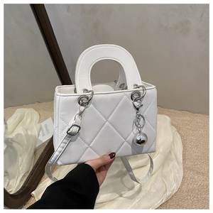 Close-up of a white quilted handbag with glossy finish and silver sphere charm