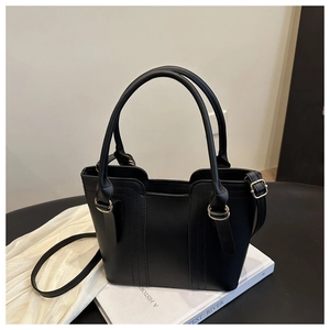 Detail of black matte PU tote bag featuring golden hardware and cylindrical handles
