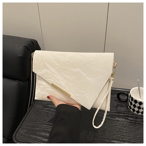 Detail of off-white pleated clutch with gold metal bar and detachable wrist strap