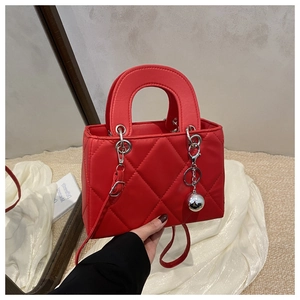 Detail of red quilted leather handbag with silver sphere charm and chain strap