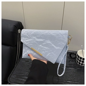 Detail of light blue pleated clutch bag with gold metallic magnetic closure and wrist strap
