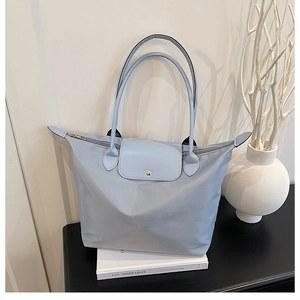 Détail d'un sac cabas en nylon bleu clair avec rabat et poignée en similicuir assortis