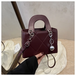 Detailed view of burgundy quilted leather handbag with silver sphere ornament and strap