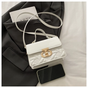 Detail of white handbag featuring geometric embossed texture and gold metal clasp closure