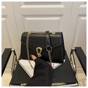 Close-up of black croc-embossed leather texture and golden fan-shaped clasp on a bag