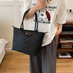 Grand sac cabas en nylon noir avec poignées en cuir et bouton pression doré sur mannequin
