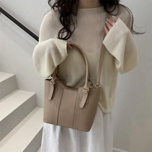 Minimalist beige leather tote bag with gold hardware shown on a model for daily commute