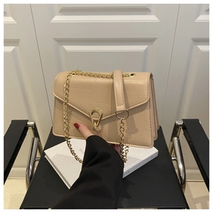 Close-up of beige crocodile pattern handbag featuring a gold horsebit buckle and chain