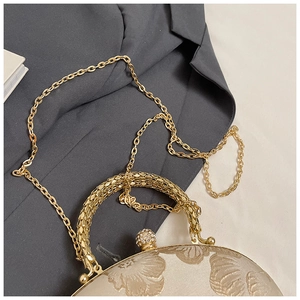Detail of champagne gold jacquard clutch bag with metal handle and diamond-encrusted clasp