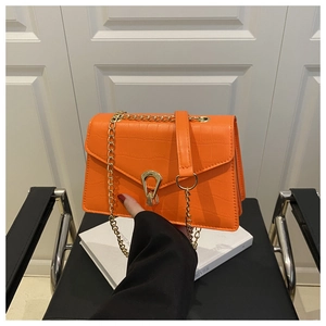 Detail of orange crocodile embossed leather bag with gold U-shaped metal lock and chain